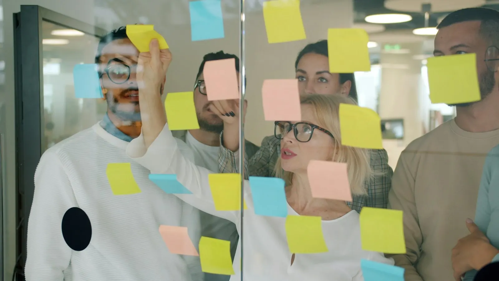 Team organising ideas with sticky notes on glass